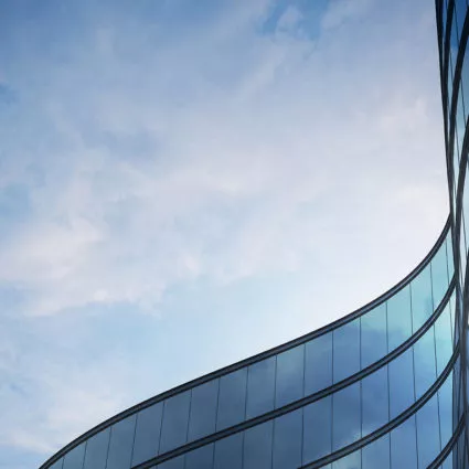 Curved outline of the top of a building with lots of side-by-side windows.
