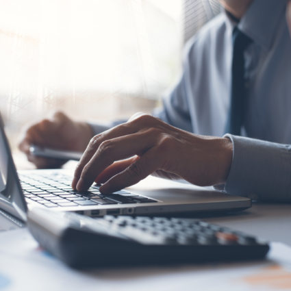 A business owner works through accounting tasks at a computer.