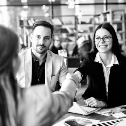Two female professionals shaking hands at an HR meeting.