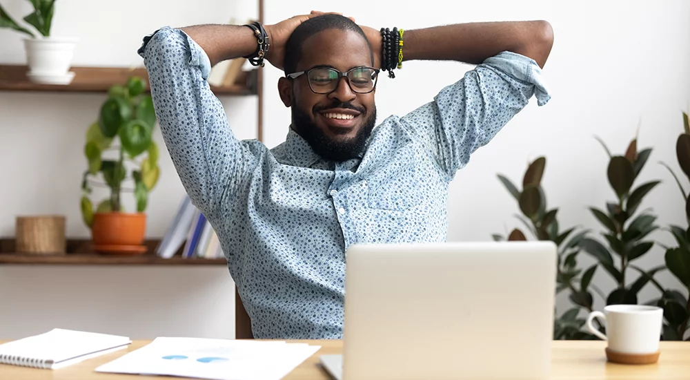 Man smiling in a relaxed position while he works on his computer.