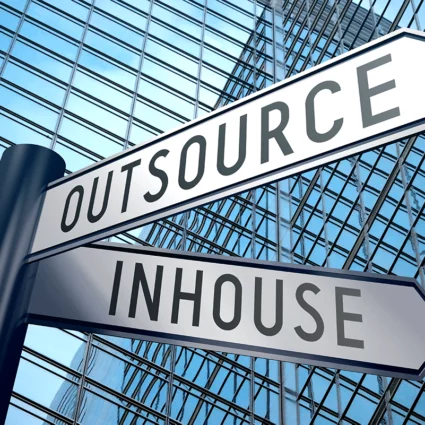 In house accounting vs. outsourcing street signs with a skyscraper in the back.