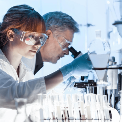 A male and female research scientist looking into microscopes.