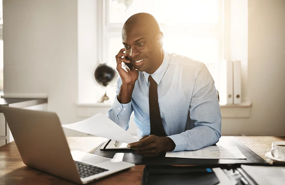 Professional male speaking on the phone while working on his laptop.