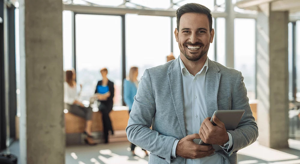 Professional male employee smiling with electronic tablet in hand.