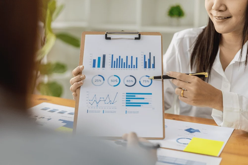 Two business professionals looking over a spreadsheet with data and graphs on it.