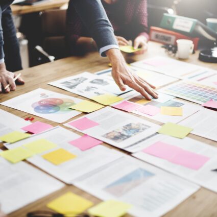 Reviewing financial documents spread out on a table with sticky notes on them.